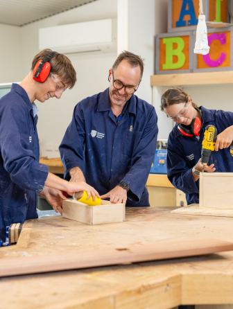 Teacher helping student with woodworking